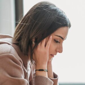 Shows a woman looking stressed out and holding her head. Represents how trauma therapy in fort worth, tx and a therapist specializing in trauma in fort worth can show you the empathy and support that you need.