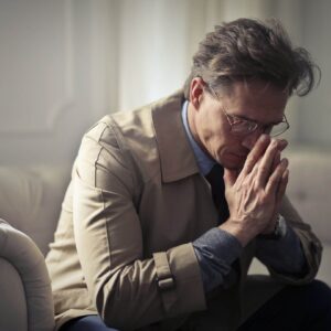 Shows a man looking sad with his hands folded. Represents how trauma therapist in fort worth, tx and trauma therapy in fort worth, tx can support you with your trauma.