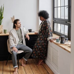 Shows a man sitting down and talking to his wife while they both are in pajamas. Represents how trauma therapy in fort worth, tx and a fort worth trauma therapist can help work through the trauma in your relationship.