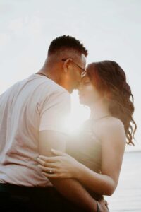 Shows a happy couple posing for a photo with the man kissing the woman's forehead. Represents how a trauma therapist for relationship trauma in fort worth, tx or a fort worth trauma therapist can help you work through the trauma that affects your relationships.